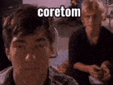 two young men are sitting in front of a sign that says coretom on it