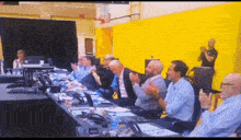 a group of people are sitting at a table clapping