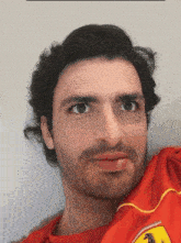 a man with a beard wearing a red shirt with a ferrari logo on it