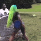 a woman with neon green hair is standing in a field .