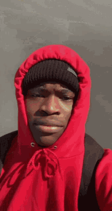 a man wearing a red hoodie and black beanie