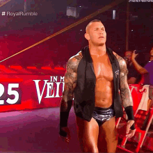 a shirtless wrestler stands in front of a sign that says 25
