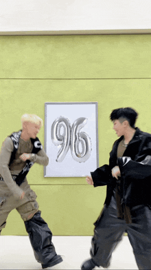two men are dancing in front of a poster that has the number 96 on it