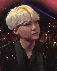 a young man with blonde hair is wearing a black suit