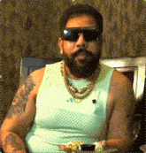 a man with a beard wearing sunglasses and a tank top with adidas on it
