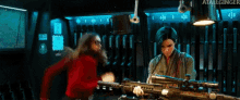 two women are standing next to each other holding guns in a room with a sign that says atallginger