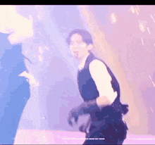a man in a suit is dancing on a stage in front of a purple background .