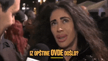 a woman is talking to a man in a crowd and the words iz opštine ovde došlo are on the bottom