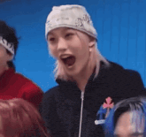 a woman wearing a beanie and a black jacket is laughing with her mouth wide open .