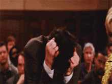 a man in a suit has his hands on his head in front of a crowd