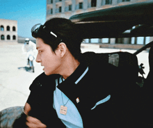a man wearing a black jacket and a blue shirt has a tag on his neck that says ' fila ' on it