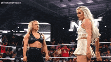 two women are standing in a wrestling ring with the word nxt on the wall