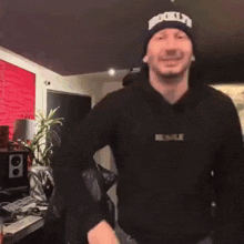a man wearing a beanie is dancing in a room .