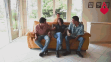 a group of people are sitting on a couch with a red heart in the background