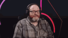 a man with a beard wearing headphones and a plaid shirt .
