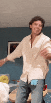 a man is dancing in a living room with his arms outstretched .