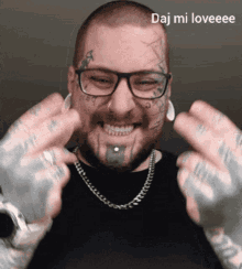 a man with glasses and a tattoo on his face is smiling and giving the middle finger