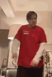 a man in a red shirt is standing in a living room .