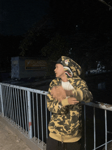 a man wearing a camo hoodie is standing on a bridge in front of a lalamove truck