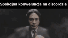 a man in a suit and tie is pointing at the camera in a video .