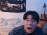 a man is making a funny face in a bedroom with a guitar and a basketball poster on the wall .