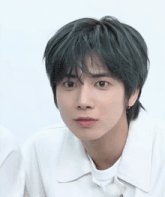 a close up of a person 's face with green hair and a white shirt