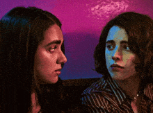 two women are looking at each other with a purple background
