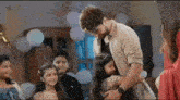 a man is holding a little girl in his arms while a group of children look on .