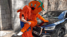 a man carrying a mascot in front of an audi