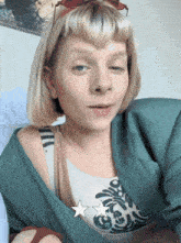 a woman with blonde hair is wearing a green jacket and a white shirt