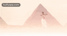 a woman in a white dress is dancing in front of a pyramid in the desert .
