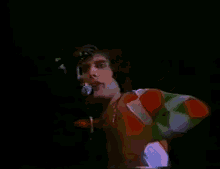 a man is singing into a microphone while wearing a colorful shirt .