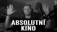 a black and white photo of a person in front of a microphone with the words absolutni kino in white letters