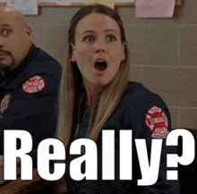 a woman with a surprised look on her face is sitting next to a man with a chicago fire department patch on his arm