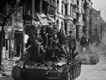 a black and white photo of soldiers riding on top of a tank ..