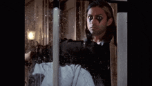 a man with paint on his face is looking out a window