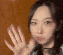 a close up of a woman 's face with her hands up .