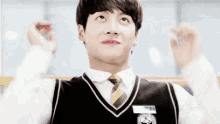 a young man wearing a vest and tie is making a funny face