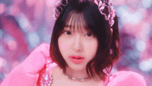 a girl in a pink dress and tiara is looking at the camera