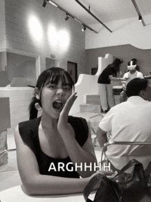 a woman sitting at a table with her mouth open and the words arghhhh written on the bottom