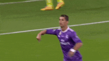 a soccer player in a purple jersey is pointing to the crowd