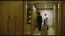 a man in a white shirt is standing in a locker room with two other men