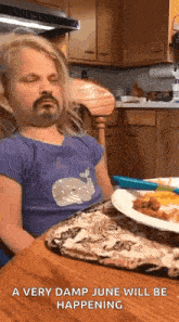 a little girl is sitting at a table with a plate of food and a very damp june will be happening .
