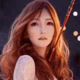 a woman with long red hair is holding a red sword in her hand .
