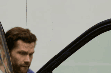 a man in a plaid shirt is getting out of a vehicle