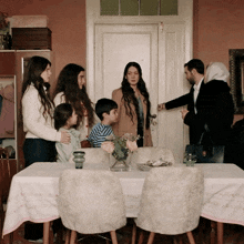 a group of people are gathered around a table with a white table cloth