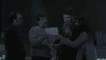 a group of people are standing in a dark room with a man holding a guitar .