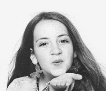 a girl with butterfly earrings blowing a kiss