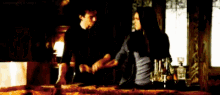 a man and a woman are sitting at a bar talking to each other and looking at each other .