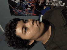 a boy with curly hair in front of a poster that says spider-man into the spider-verse